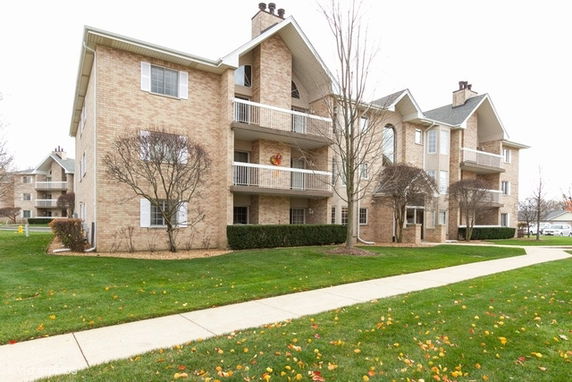Front view of a multi-story apartment building with balconies and a brick exterior.
