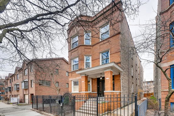 Front view of a three-story brick building with a fenced entrance.