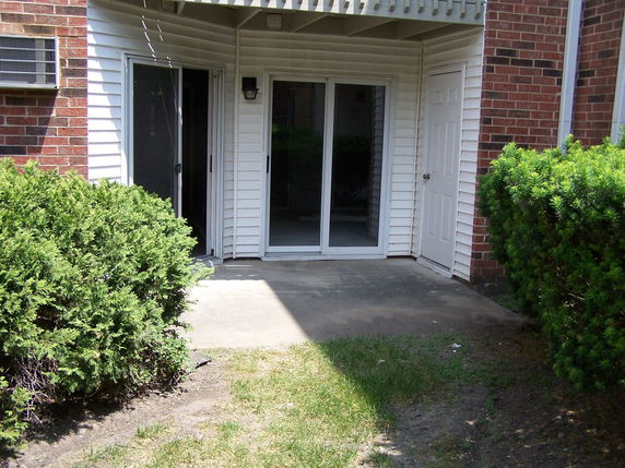 Back view of a house with sliding glass doors and a small concrete patio.
