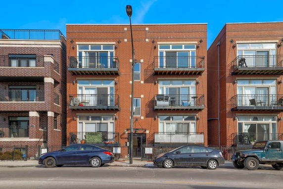 Front view of a multi-story brick apartment building with balconies.