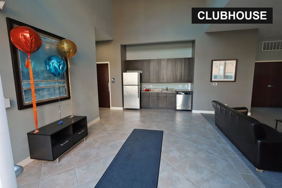 Interior view of a clubhouse with a kitchenette and seating area.
