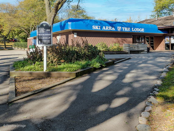 Front view of a lodge with a blue awning labeled 'Ski Area The Lodge'.