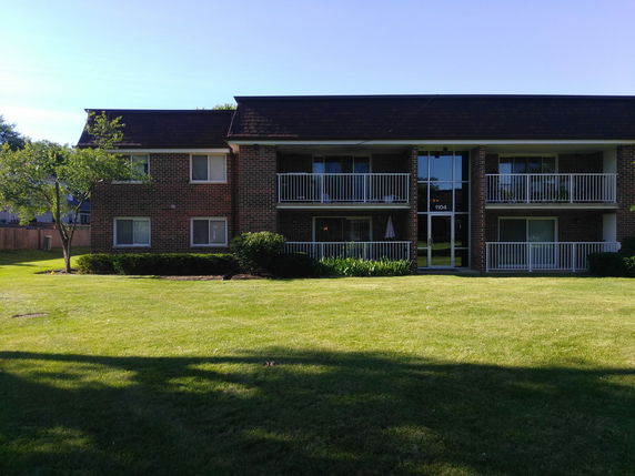 Front view of a two-story brick apartment building with balconies.