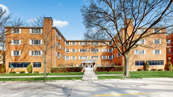 Front view of a multi-story brick apartment building with a central entrance.
