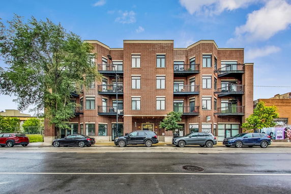 Front view of a multi-story brick building with balconies and multiple windows.