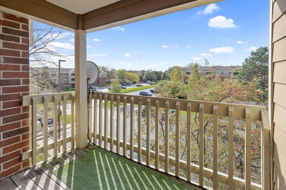 View from a balcony overlooking a residential area with trees and parked cars.