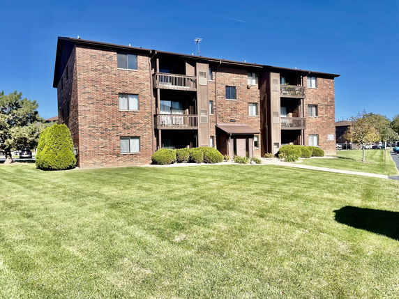 Front view of a three-story brick apartment building with balconies.