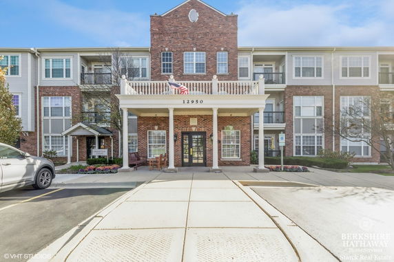 Front view of a multi-story brick building with a covered entrance and balcony.