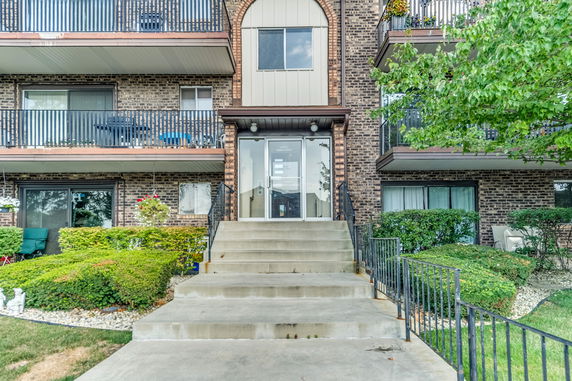 Front view of a multi-story brick apartment building with a glass entrance and balconies.