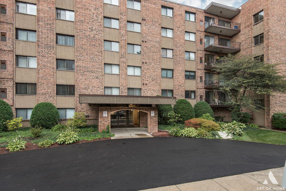 Front view of a multi-story brick apartment building with a small entrance canopy.