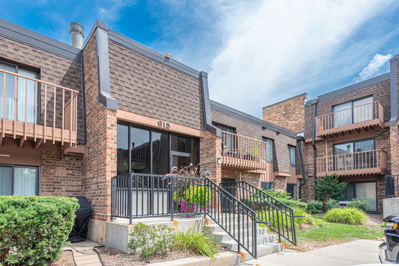 Front view of a residential building with balconies and brick facade.