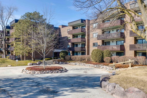 Front view of a multi-story brick apartment building with balconies.