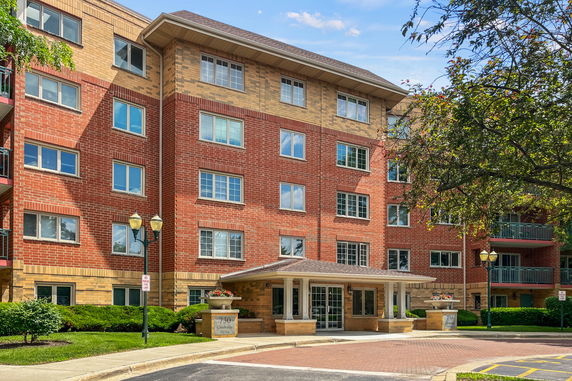 Front view of a multi-story brick building with multiple windows and a covered entrance.