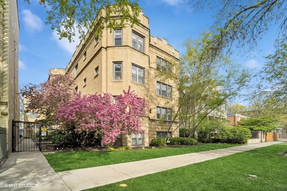 Front view of a multi-story brick building with landscaping and sidewalk.
