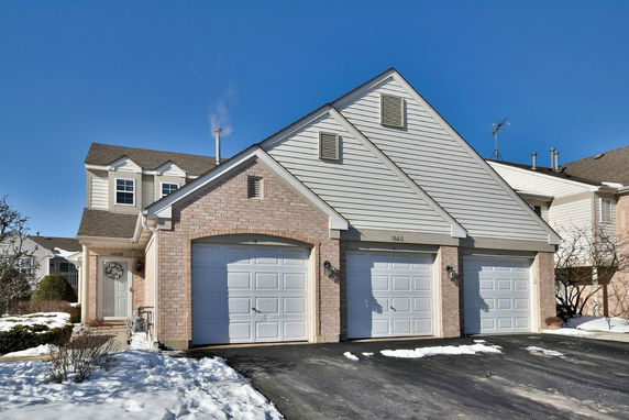 Front view of a house with two garage doors and brick siding.