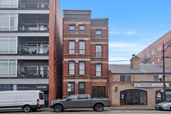 Front view of a multi-story brick building adjacent to modern structures.