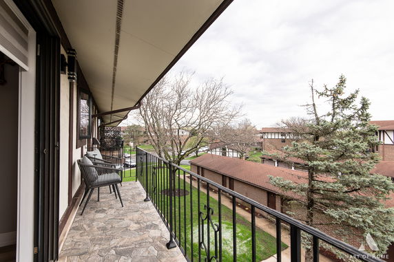 View from a balcony overlooking a residential area with trees and a walkway.