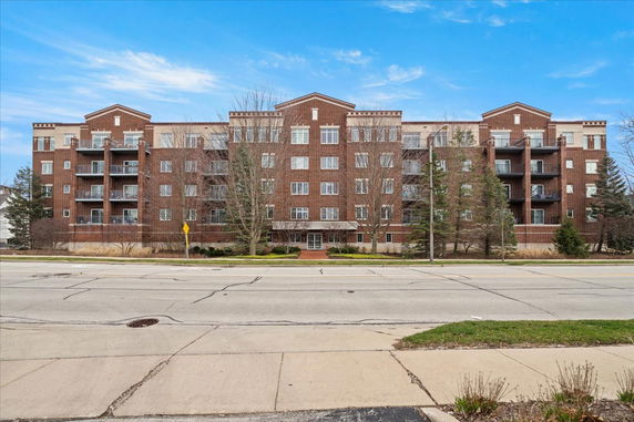 Front view of a multi-story brick apartment building with balconies.