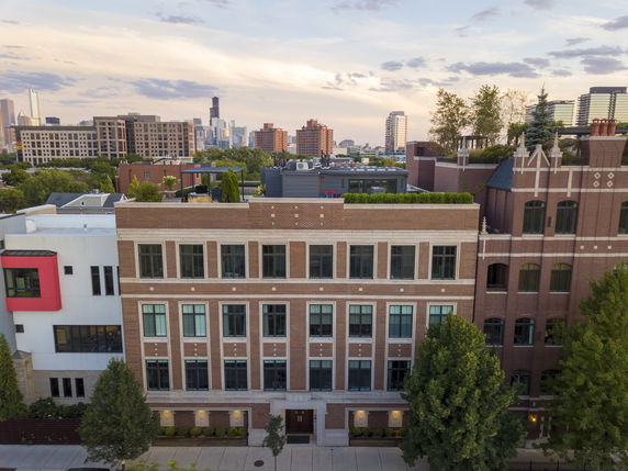 Front view of a multi-story brick building with large windows.