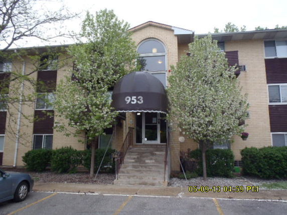 Front view of a three-story apartment building with a central entrance and an overhang.