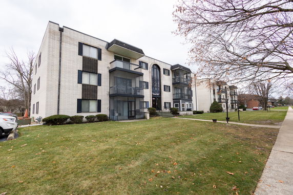 Front view of a multi-story apartment building with balconies and brick exterior.