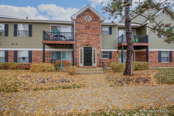 Front view of a two-story brick and siding building with balconies and a central entrance.