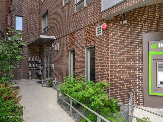 Front view of a brick building entrance with an ATM.