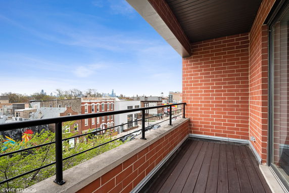 View from a balcony showing surrounding buildings and distant skyline.