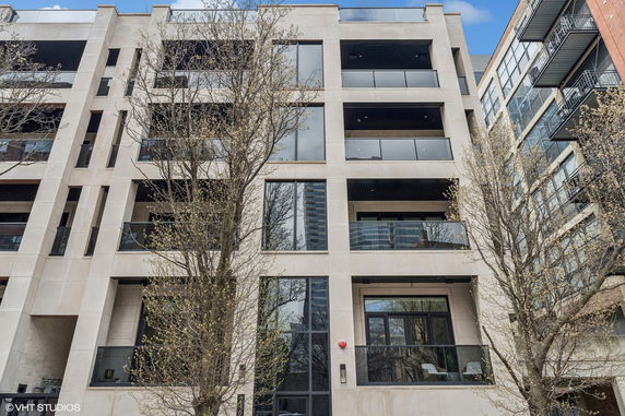 Front view of a modern multi-story apartment building with large glass balconies.