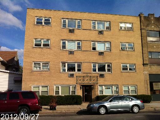 Front view of a multi-story brick building with several windows and a central entrance.