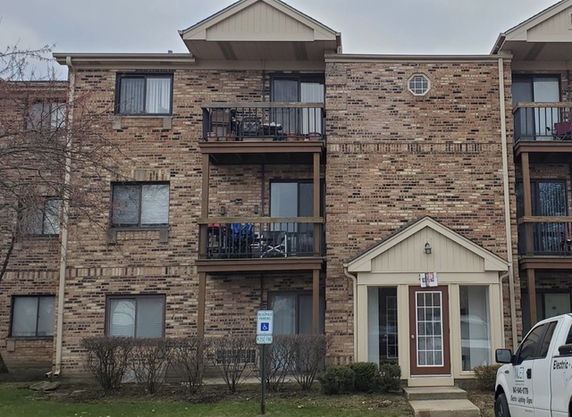 Front view of a multi-story brick apartment building with balconies.