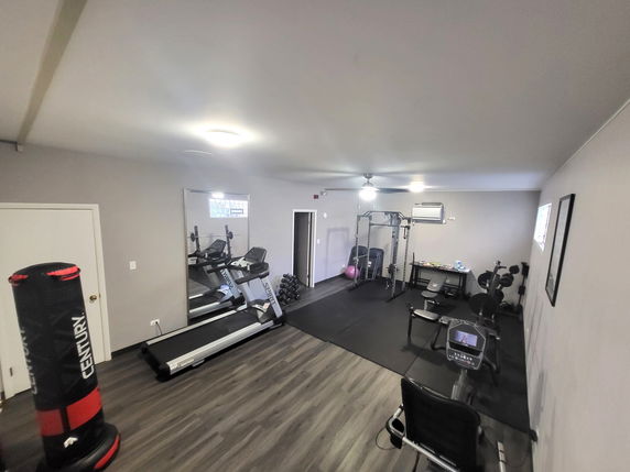 Room set up as a personal gym with exercise equipment and a punching bag.
