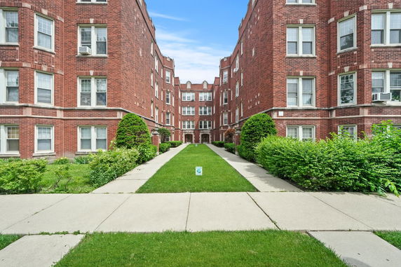 Front view of a brick apartment building with a central walkway.