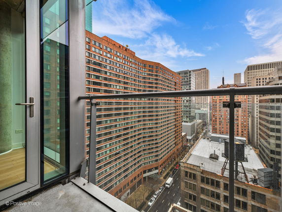 View of surrounding buildings from a balcony with glass railing.
