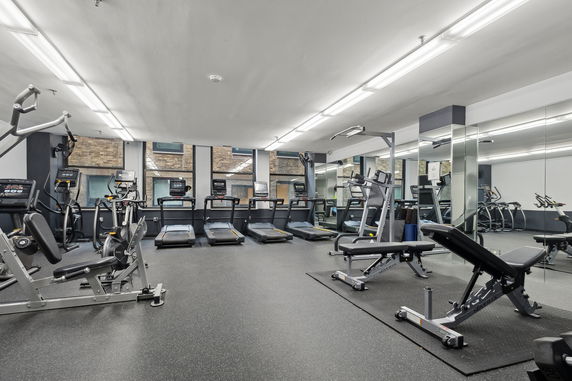 Indoor gym area with various exercise equipment including treadmills and weight benches.