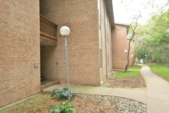 Side view of a brick residential building with a pathway and lamp posts.