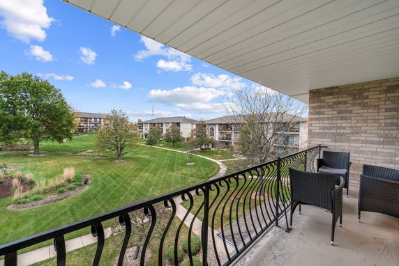 View from a balcony overlooking a landscaped courtyard with walking paths and surrounding buildings.