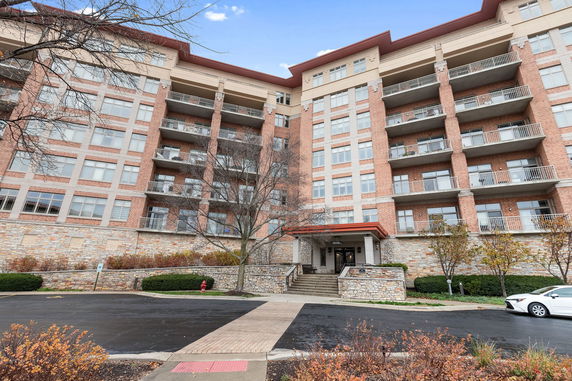 Front view of a multi-story brick apartment building with balconies.