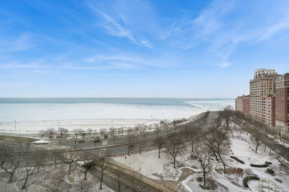Panoramic view of a snowy landscape with a coastal road and buildings along the shore.