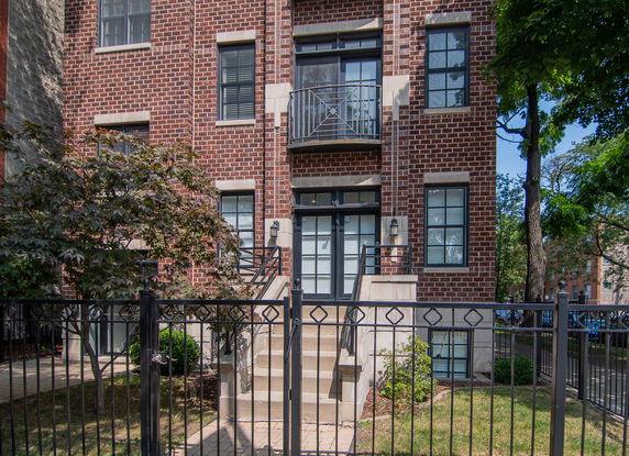 Front view of a multi-story brick building with multiple windows and a small balcony.