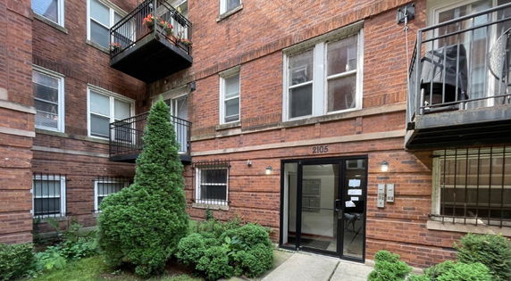 Front view of a brick apartment building with balconies.