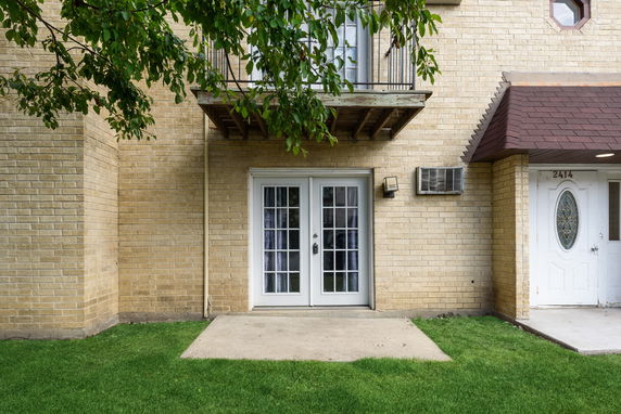 Front view of a building with a brick exterior and two doors, one with glass panels and one with decorative glass.