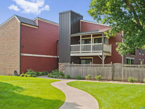 Front view of a multi-story house with red siding and a small balcony.