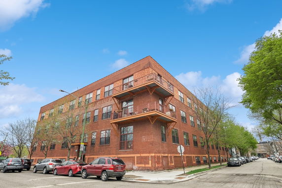 Front view of a brick multi-story building with balconies.