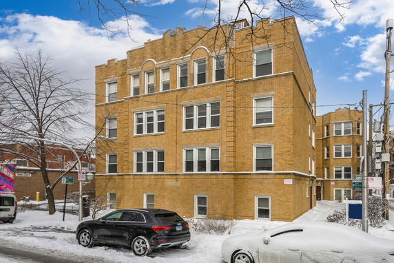 Front view of a multi-story brick apartment building covered in snow.