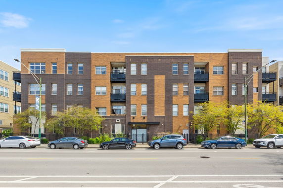 Front view of a four-story apartment building with a mix of brown and black brick facade.
