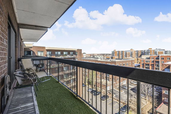 Panoramic view from a balcony overlooking city buildings and a parking area.