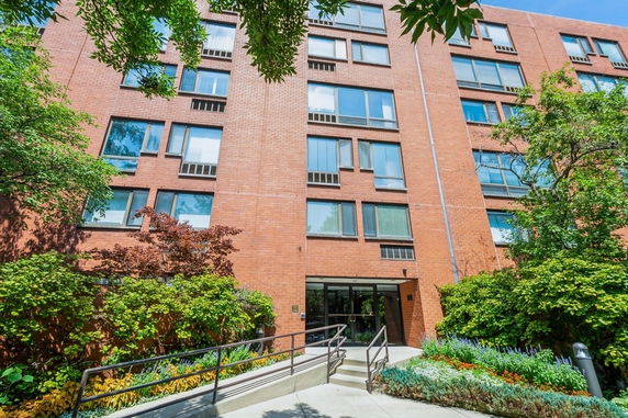 Front view of a multi-story brick building with numerous windows and an entryway.