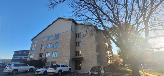 Front view of a multi-story apartment building with parking space.