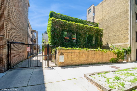 Front view of a two-story building covered in green ivy.